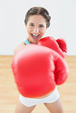 Beautiful playful woman in red boxing gloves at fitness studio