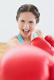 Beautiful young woman in red boxing gloves at fitness studio
