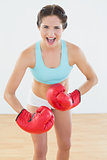 Woman in red boxing gloves flexing muscles at fitness studio