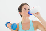 Fit woman with dumbbell drinking water