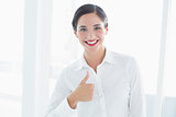 Smiling young business woman gesturing thumbs up