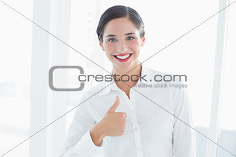 Smiling young business woman gesturing thumbs up