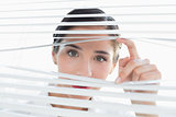 Young business woman peeking through blinds