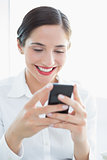 Smiling business woman looking at mobile phone