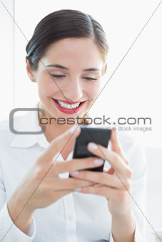 Smiling business woman looking at mobile phone