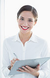 Portrait of a smiling business woman with clipboard and pen