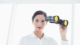 Serious business woman  with binoculars in office