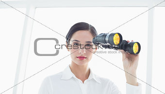 Serious business woman  with binoculars in office
