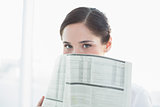 Business woman holding newspaper in front of face