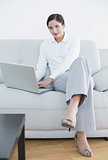 Portrait of a well dressed woman using laptop on sofa