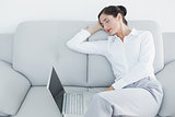 Well dressed woman resting while using laptop at home
