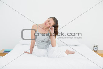 Sleepy young woman sitting in bed