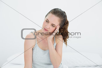 Woman with headache sitting in bed