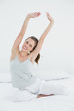 Smiling woman stretching her arms up in bed