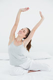 Woman stretching her arms up in bed