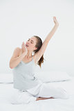 Woman stretching arms while yawning in bed