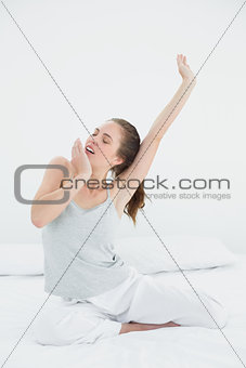 Woman stretching arms while yawning in bed