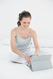 Casual woman using tablet PC in bed