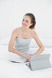 Woman with tablet PC looking away in bed