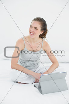 Woman with tablet PC looking away in bed
