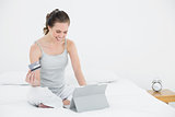 Woman doing online shopping in bed