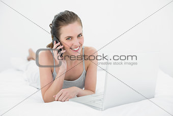 Portrait of a smiling casual woman using cellphone and laptop