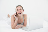 Cheerful casual woman using cellphone and laptop