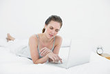 Casual woman using laptop in bed