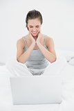 Smiling casual woman looking at laptop in bed