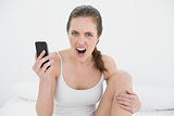 Portrait of a woman shouting with mobile phone in hand