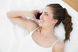 Smiling woman using mobile phone in bed