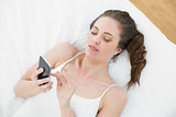 Relaxed woman using mobile phone in bed