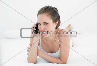 Portrait of a smiling woman using mobile phone in bed