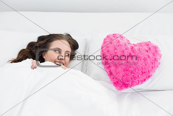 Woman lying in bed with heart  shaped pillow cover