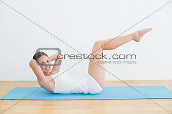 Smiling woman doing stomach crunches on exercise mat