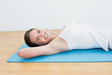 Smiling young woman lying on exercise mat