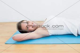 Smiling young woman lying on exercise mat