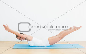 Side view of a smiling woman exercising on mat