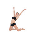 Smiling sporty woman jumping on white background