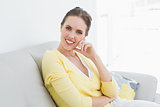 Smiling relaxed woman sitting on sofa at home