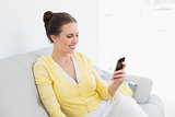 Smiling woman using mobile phone at home