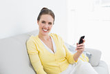 Smiling woman with mobile phone on sofa