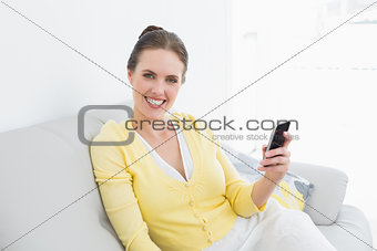 Smiling woman with mobile phone on sofa