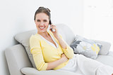 Portrait of a smiling woman using mobile phone on sofa