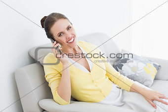Portrait of a smiling woman using mobile phone on sofa
