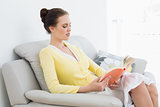 Woman reading a book on sofa at home