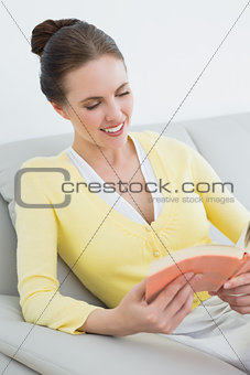 Smiling woman reading a book on sofa
