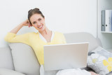 Smiling casual woman with laptop sitting at home