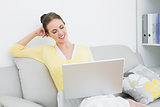 Smiling casual woman using laptop at home