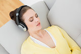 Woman lying on sofa and listening music through headphones